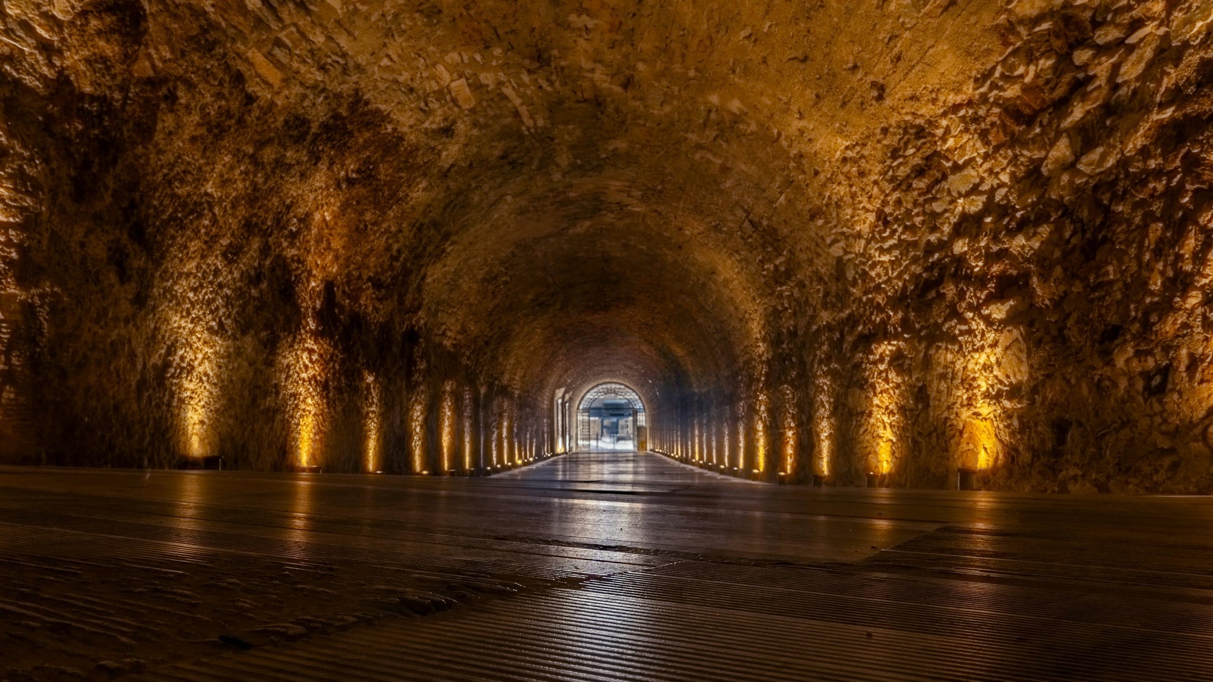 A stone tunnel opening onto the light of an arena.