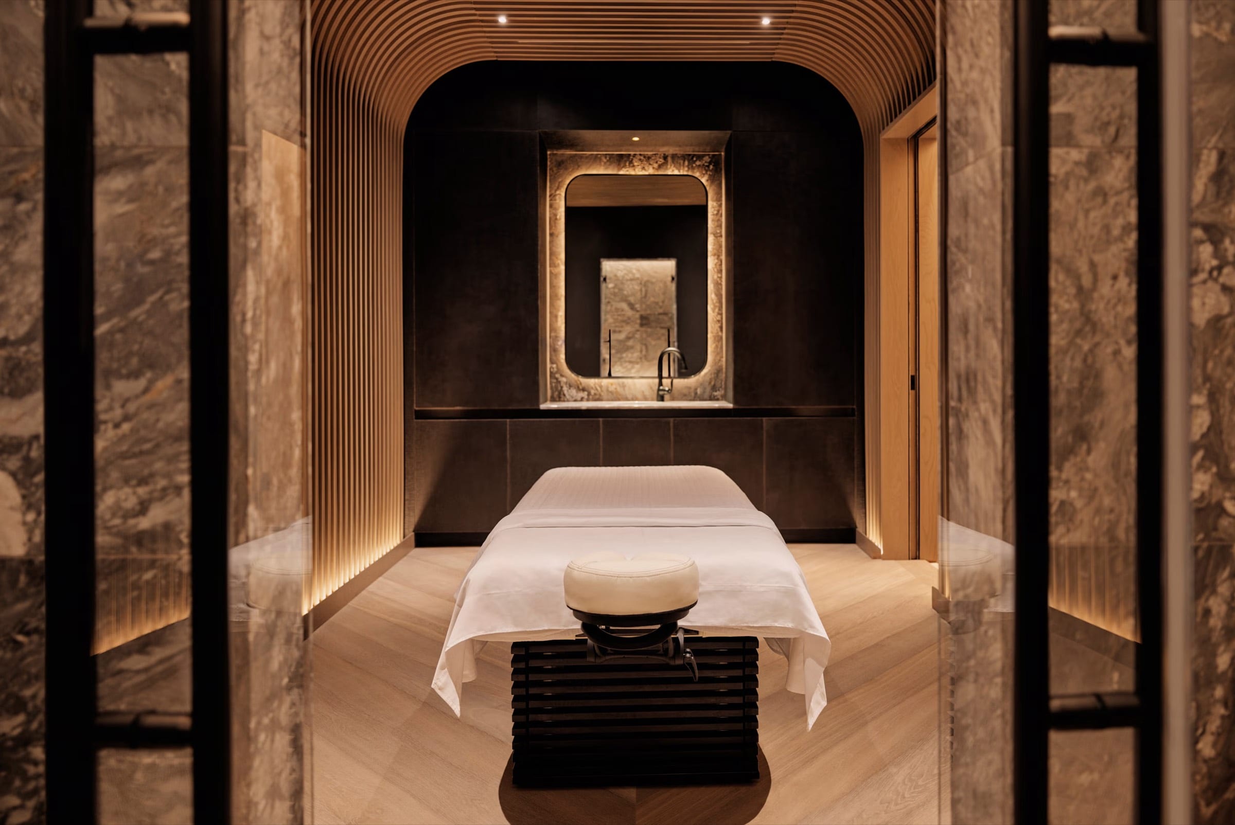 A private room in stone and pale wood, prepared, lit low.